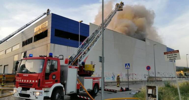Una quinzena de dotacions de Bombers treballa per extingir un incendi en dues naus industrials a la Garriga